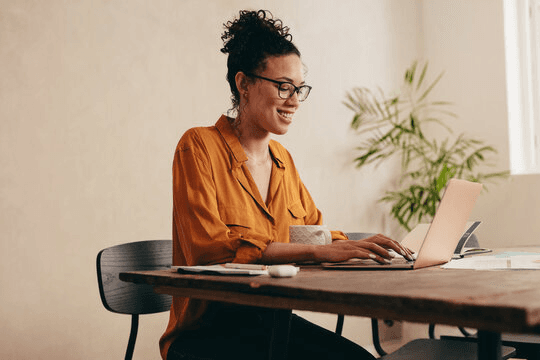 Woman working on a laptop in a well-lit room.